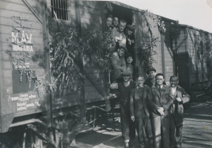 Munkaszolgálatosok egy ágakkal díszített marhavagon előtt állnak