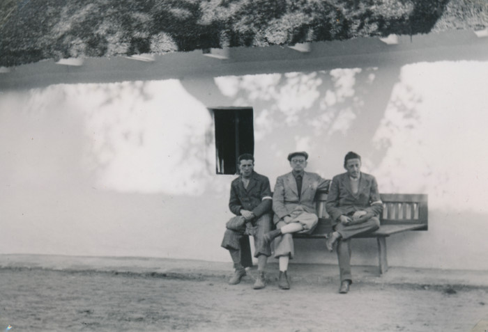 Három munkaszolgálatos (Vig Farkas, Spitzer Dénes, Lőwinger László) ül egy padon a tető alatt