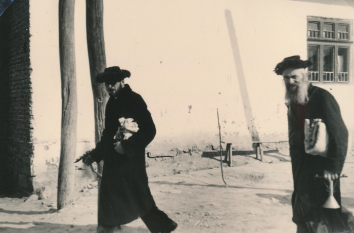 Két ortodox zsidó férfi imasálat és gyertyatartót cipel egy zsidó ünnepen
