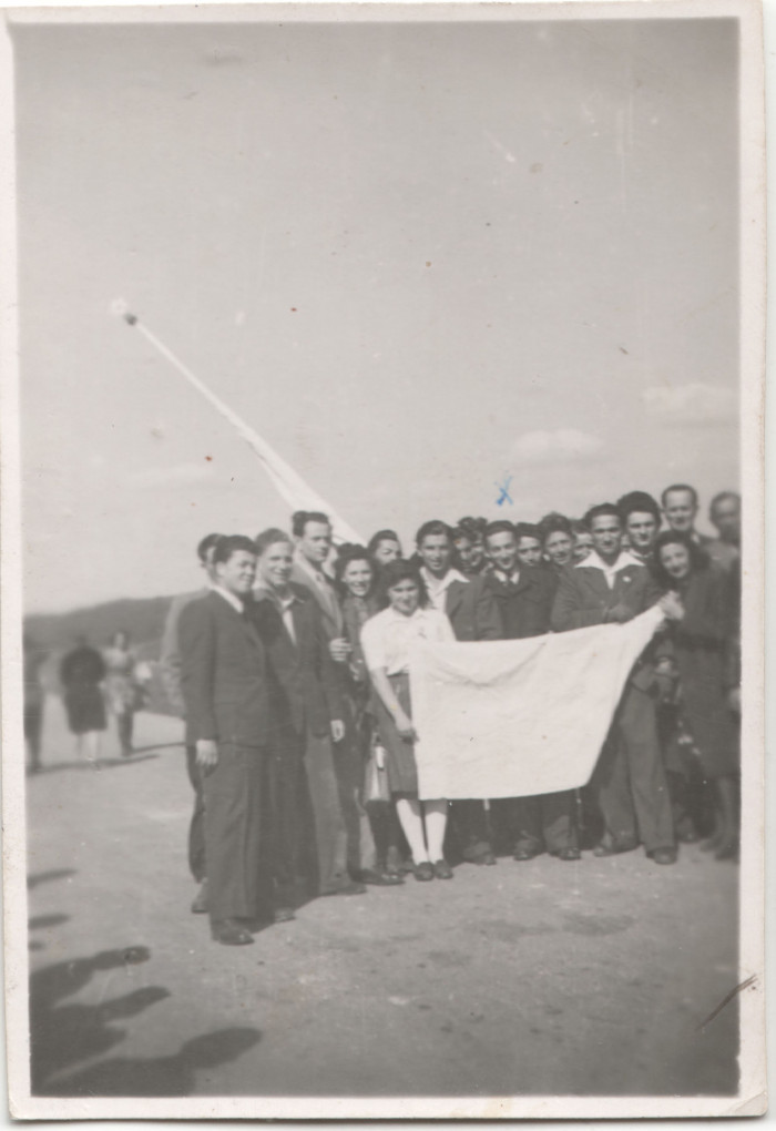 Emlékezők egy csoportja fehér zászlóval (feliratos lepellel), az egykori deportálás helyszínén