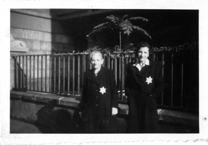 Két nő sárga csillaggal egy ház kerítés előtt